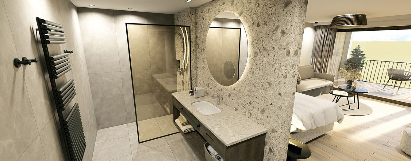 Moderne, offenes Zimmer mit einem durch eine strukturierte Wand abgetrennten Badezimmer mit rundem Spiegel, Waschbecken, begehbarer Dusche und sichtbarem Schlafbereich mit Bett, Sitzecke und Balkonblick.