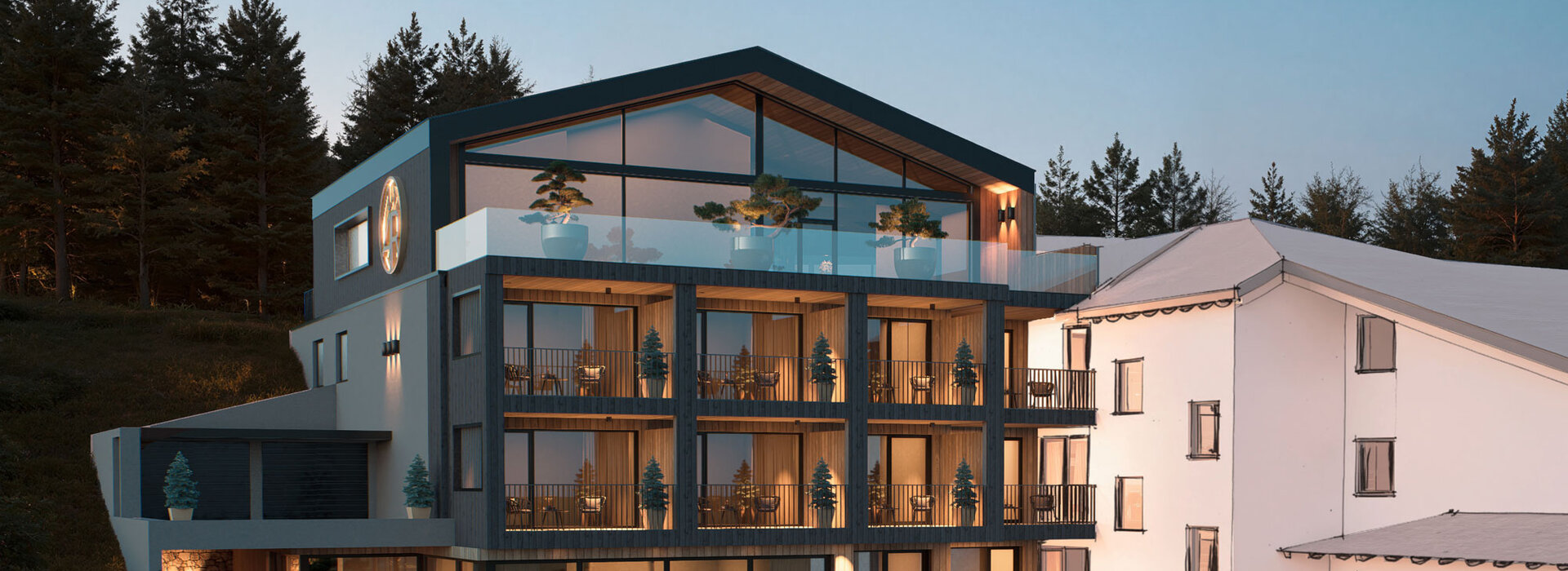 Modernes mehrstöckiges Gebäude mit großen Glasfenstern und Balkonen, abends warm beleuchtet. Angrenzend an ein weißes traditionelles Gebäude, umgeben von Bäumen, mit einem begrünten Vorgarten.