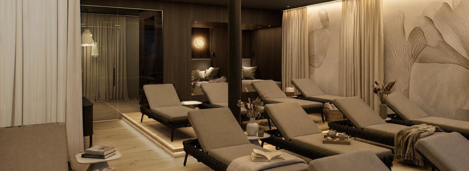 Ein ruhiger Spa-Ruheraum mit mehreren gepolsterten Wellnessliegen, sanfter Beleuchtung, dekorativen Deckenleuchten, transparenten Vorhängen und beruhigenden Neutraltönen, die eine ruhige und einladende Atmosphäre schaffen.