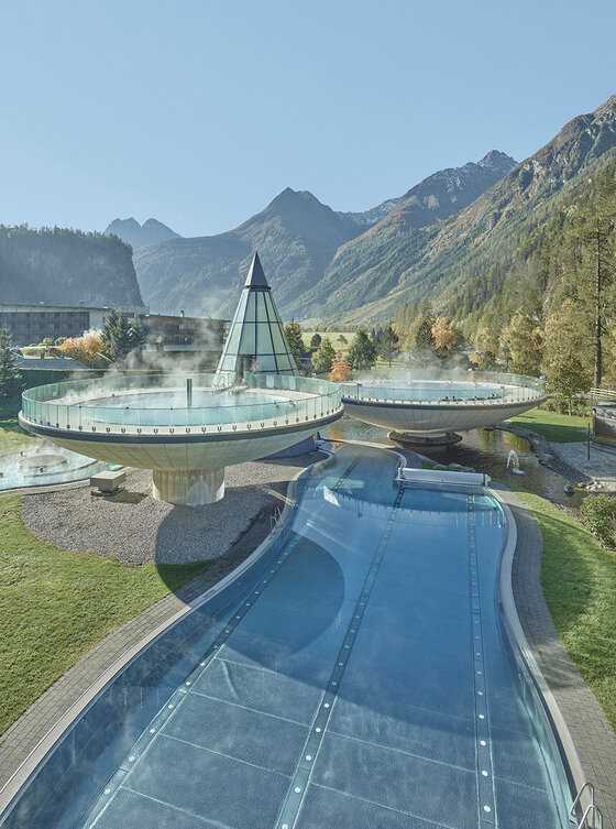 Ein Bild vom Aqua Dome mit Glaspyramide, Pools und einer Berglandschaft im Hintergrund unter freiem Himmel.